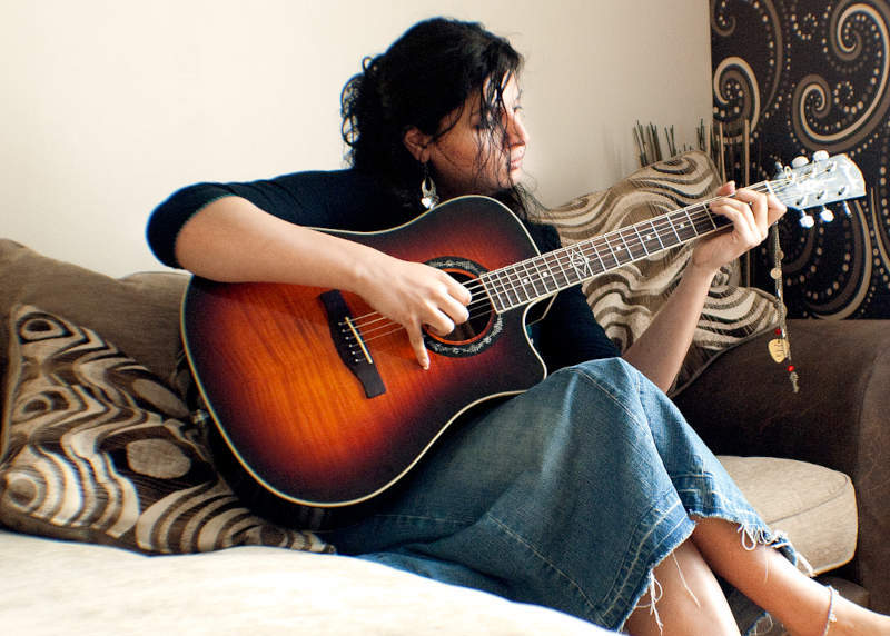 Maddi sitting on sofa playing a guitar